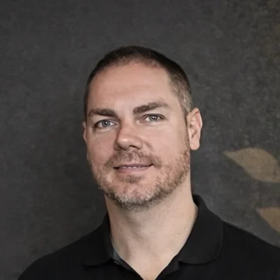 Chiropractor Jamie Stephens In Front Of Grey Wall